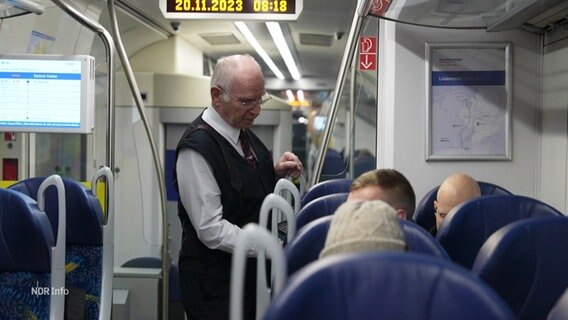 Zugbegleiter Uwe Huxol kontrolliert die Fahrkarten von Passagieren. © Screenshot 