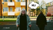 Eine ältere Dame geht eine Straße entlang. Über ihrem Kopf schwebt eine Comic-Sprechblase, darin ist das Wort "Hey" zu lesen. © Screenshot 