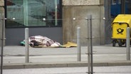Ein obdachlose Person liegt auf der Straße unter einer Decke. © Screenshot 