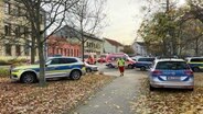 Mehrere Polizeiwagen und Rettungswagen stehen auf einem Platz. © Screenshot 