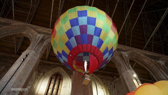 Ein kleiner Heißluftballon fliegt unter die Decke einer Kirche. © Screenshot 