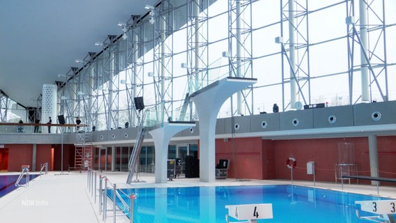 In einer modernen Schwimmhalle sind zwei Sprungtürme zu sehen. © Screenshot 