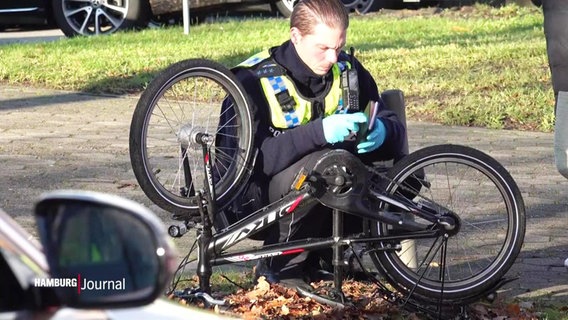 Ein Polizist untersucht das Fahrrad des angefahrenen Kindes in Neuengamme. © Screenshot 