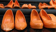 Orangene Schuhe stehen auf einer Treppe. © Screenshot 