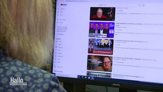 Eine Frau schaut auf ein Display auf dem eine Liste von Videos zu sehen ist. © Screenshot 