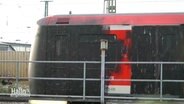 Komplett schwarz besprühte S-Bahn steht am Bahngleis. © Screenshot 