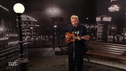 Robert Stadlober mit Akkustikgitarre und Mikrofon vor schwarzem Hintergrund. © Screenshot 