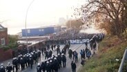Polizei und HSV-Fans mit Banner und Fahnen laufen durch eine Straße. © Screenshot 