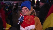 Eine Person mit Deutschland Fan-Artikeln im Interview. © Screenshot 