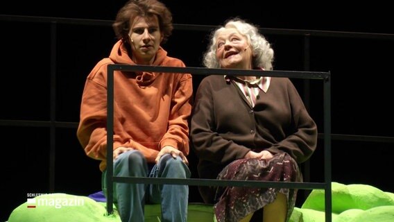 Eine ältere Frau und ein junger Mann auf einer Bühne. © Screenshot 