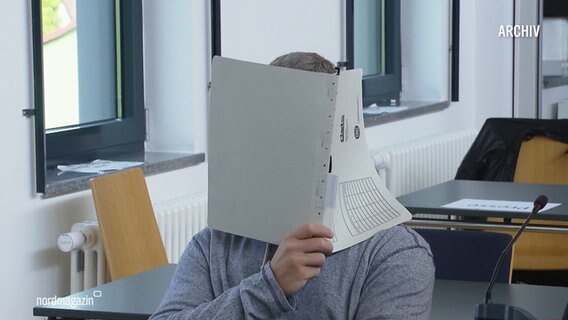 Eine Person hält sich eine Akte vor das Gesicht. (Archivbild) © Screenshot 