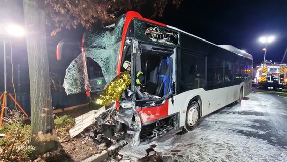 Der verunglückte Linienbus am Unfallort: Die Front ist komplett eingedrückt, die Frontscheibe zersplittert. Ein Feuerwehrmann ist im Führerstand. © Screenshot 