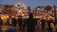 Szenerie auf einem Weihnachtsmarkt mit Lichterketten, Riesenrad und Essensständen. © Screenshot 