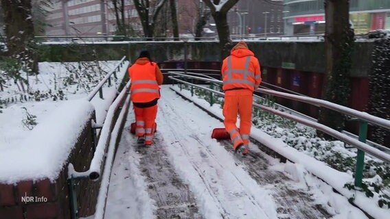 Zwei Männer räumen Schnee von einer Straße. © Screenshot 