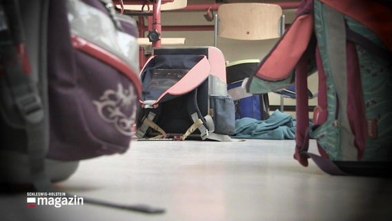 Schulranzen stehen auf dem Fußboden eines Klassenraums. © Screenshot 