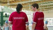 Zwei Personen der Wasserrettung des DRK im Schwimmbad mit Kindern. © Screenshot 