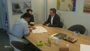 Der SPD-Fraktionsvorsitzende im Schleswig-Holsteinischen Landtag, Thomas Losse-Müller, sitzt mit zwei anderen Personen an einem Tisch. © Screenshot 