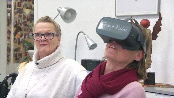 Zwei Personen sitzen nebeneinander und eine trägt eine VR-Brille. © Screenshot 