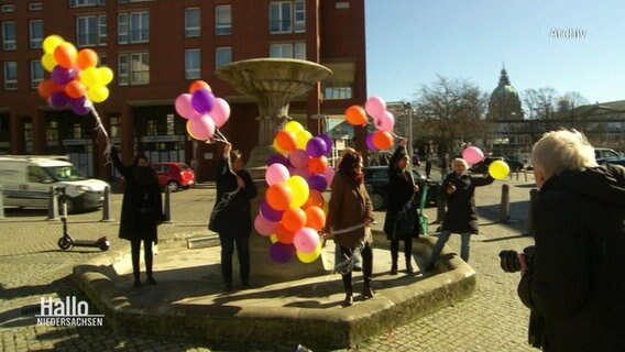 Einige Menschen halten bunte Luftballons in die Luft. © Screenshot 