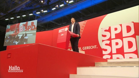 Lars Klingenbeil steht auf einer Bühne und hält eine Rede. © Screenshot 