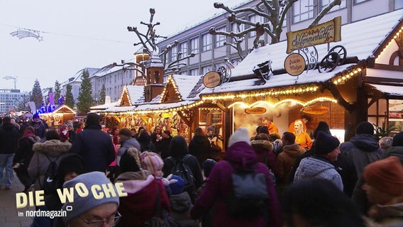 Blick über die Köpfe einer Menschenmenge hinweg, die sich auf einem Weihnachtsmarkt tummelt. © Screenshot 