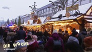Blick über die Köpfe einer Menschenmenge hinweg, die sich auf einem Weihnachtsmarkt tummelt. © Screenshot 