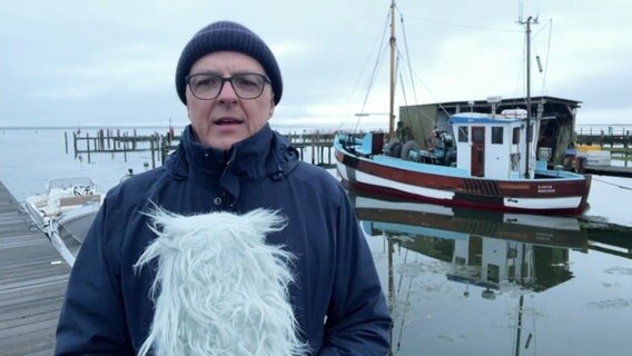Stefan Kreibohm steht auf der Insel Hiddensee vor einem Fischkutter. © Screenshot 