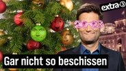 Christian Ehring mit einer rosaroten 2023-Brille neben einem geschmückten Weihnachtsbaum. Wie geil war 2023?! (extra 3 vom 13.12.2023 im NDR Fernsehen) © NDR 