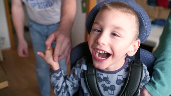 Ein behinderter Junge spielt mit seinen Eltern und lacht. © Screenshot 