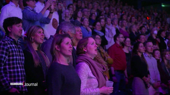 Die Ränge in der Barclays Arena gefüllt mit Menschen, die singen. © Screenshot 