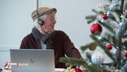 Ein Mann sitzt mit Headset vor einem Laptop, an der Seite steht ein Weihnachtsbaum. © Screenshot 