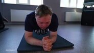 Ein junger Mann mit Trisomie 21 macht Planking. © Screenshot 