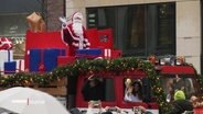 Ein Weihnachtsmann und ein Christkind winken Schaulustigen in der Hamburger Innenstadt von einem Weihnachtstruck zu. © Screenshot 