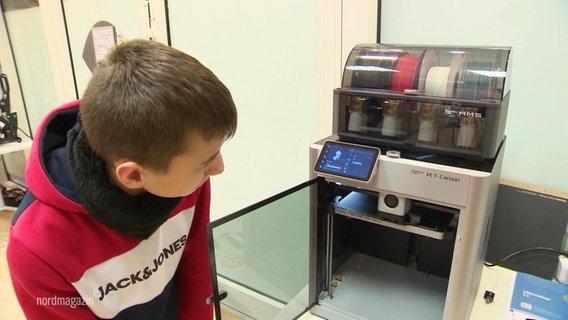 Ein Junge stellt eine kleine Figur mit einem 3D-Drucker her. © Screenshot 