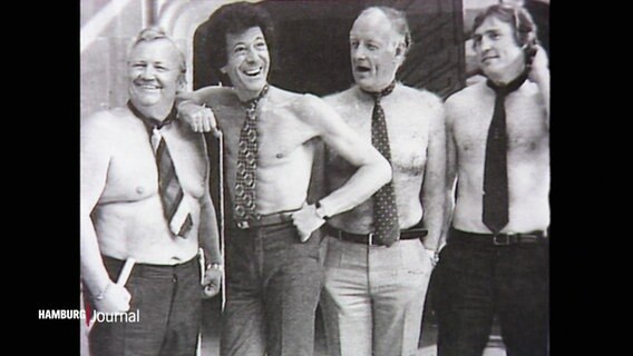 Vier Männer posieren mit freiem Oberkörper und um den Hals gebundenen Krawatten auf einem älteren Schwarz--Weiß-Foto. © Screenshot 