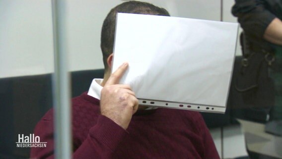 Eine Person in einem Gerichtssaal verdeckt sein Gesicht. © Screenshot 