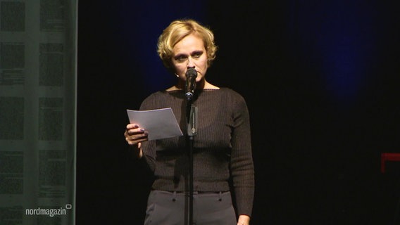 Caren Miosga spricht in ein Mikrofon auf einer Bühne. © Screenshot 
