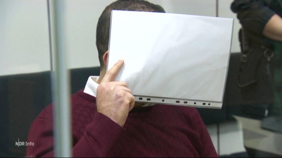 Eine Person in einem Gerichtssaal verdeckt sein Gesicht. © Screenshot 