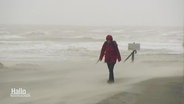 Eine Frau geht im Sturm am Nordseestrand spazieren. © Screenshot 