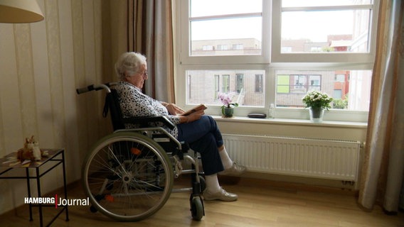 Eine Seniorin sitzt in einem Rollstuhl und liest ein Buch. © Screenshot 