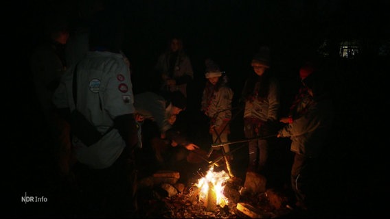 Eine Pfadfindergruppe steht an einem Lagerfeuer. © Screenshot 