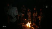 Eine Pfadfindergruppe steht an einem Lagerfeuer. © Screenshot 