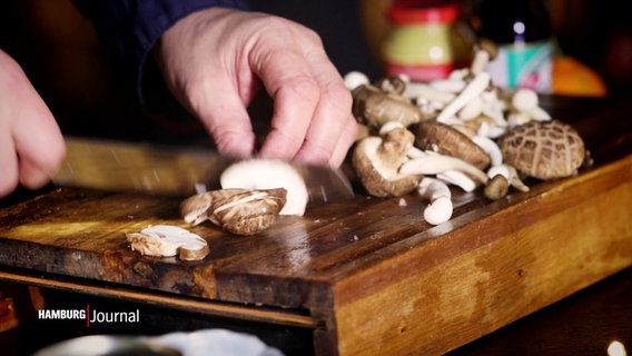 Pilze werden auf einem Holzbrett geschnitten. © Screenshot 