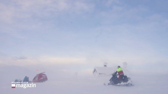 Menschen mit Schneemobilen in einer weißen Landschaft. © Screenshot 