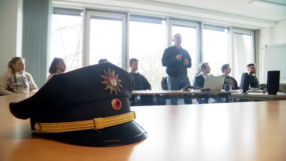 Eine Polizei-Mütze liegt bei einer Konferenz auf einem Tisch. © Screenshot 