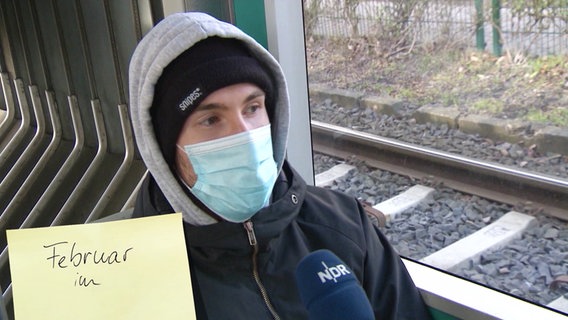 Ein junger Mann sitzt mit einer Maske in einem Zug. © Screenshot 