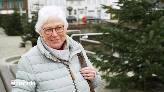 Eine ältere Dame steht bei einem Straßeninterview lächelnd neben einem Tannenbaum. © Screenshot 