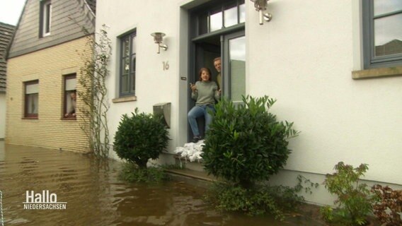Zwei Personen in einem Hauseingang, die Straße davor ist unter Wasser. © Screenshot 