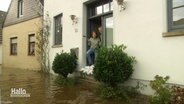 Zwei Personen in einem Hauseingang, die Straße davor ist unter Wasser. © Screenshot 