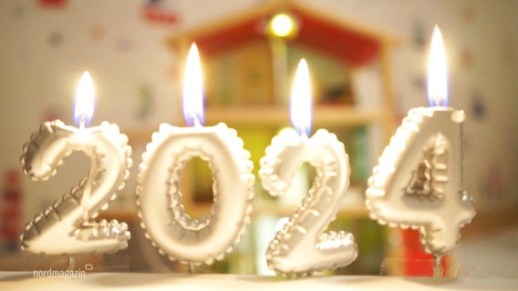 Brennende Kerzen in Zahlenform bilden die Zahl 2024. © Screenshot 